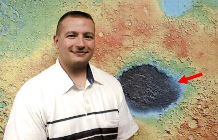Picture of Scott Mest in front of an image of Mars Topography. A red arrow shows location of the geologic map.
